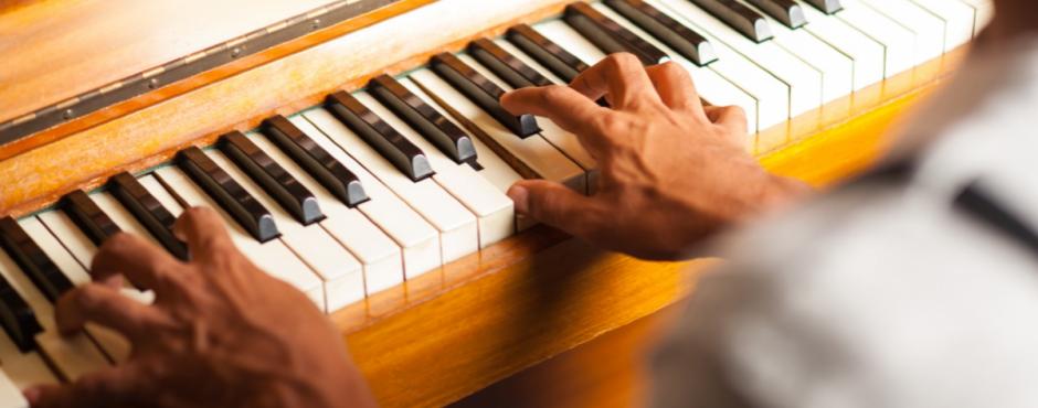 En mand iført baret spiller passioneret på klaver med hænderne ved Legatudvalget 2019-arrangementet.