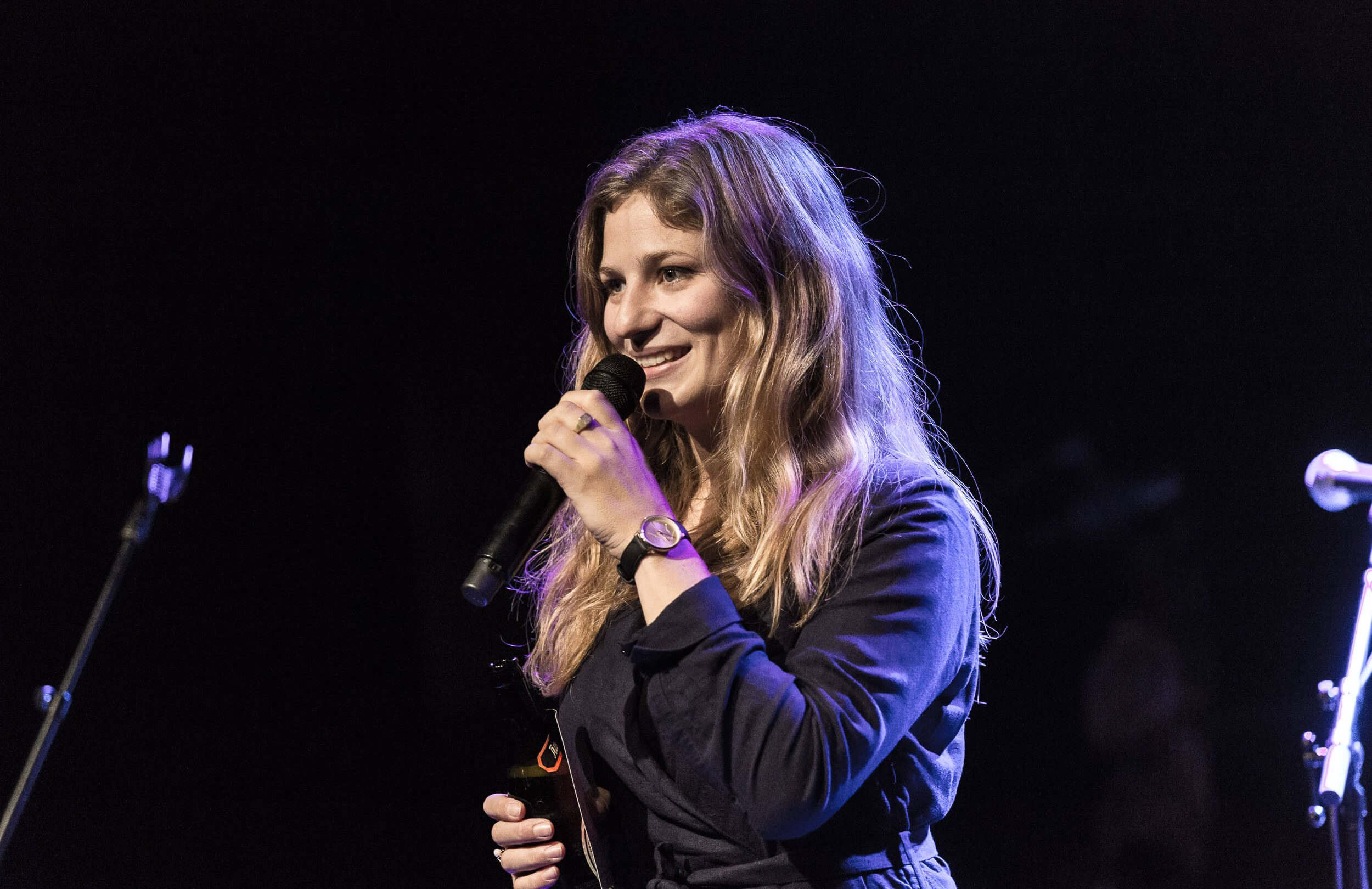 En kvinde synger i en mikrofon på scenen under et Kulturpolitisk arrangement.