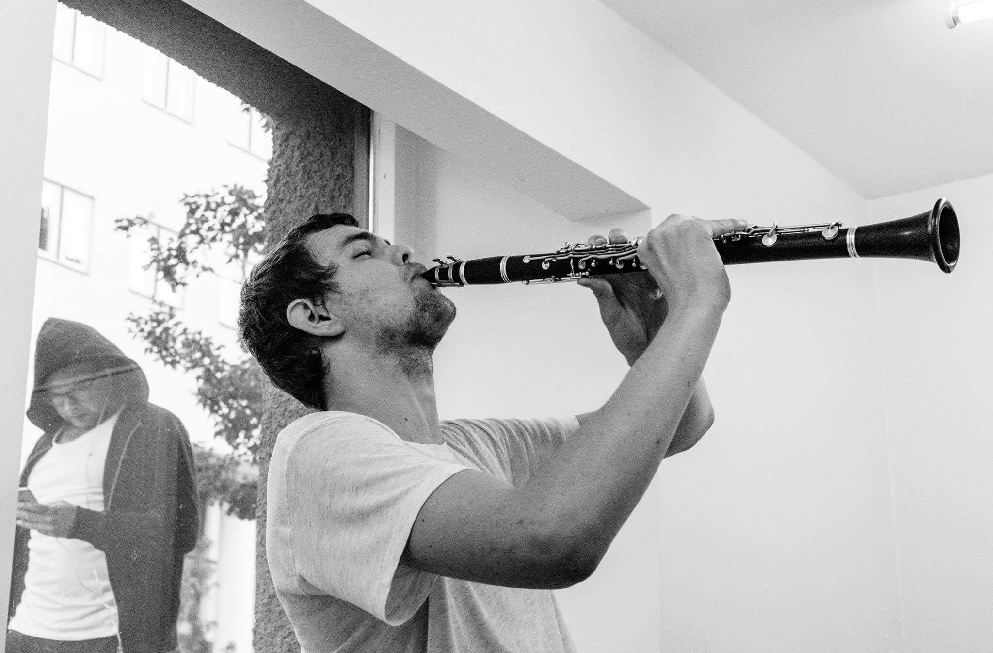 Andreas Røysum, medlem af netværket Mandagsklubben, spiller passioneret sin klarinet foran et vindue.
