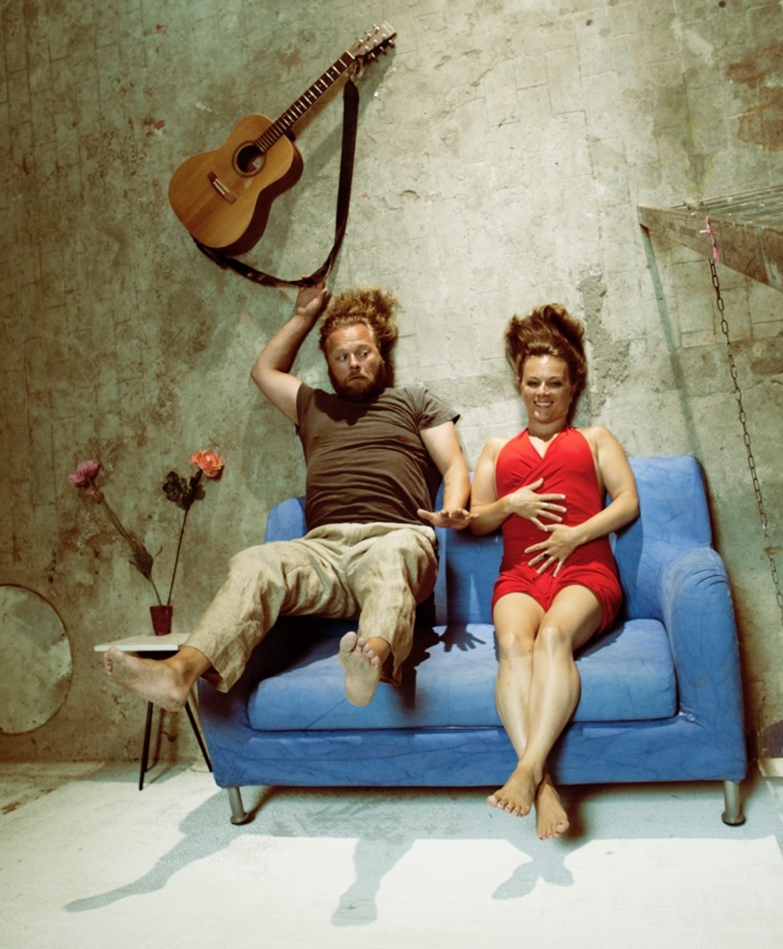 Et elegant par sidder på en blå sofa i Klubben Vest og nyder en koncert eller middag.