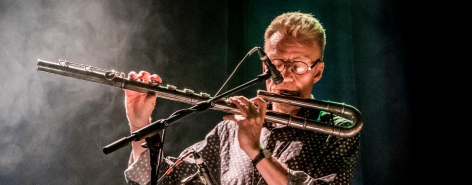 Fredrik Lundin, en mand med briller, spiller fløjte på scenen.