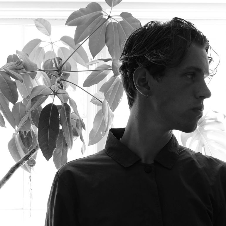 Et sort/hvidt foto af en mand, der står foran en plante, der fanger essensen af tid og søge.