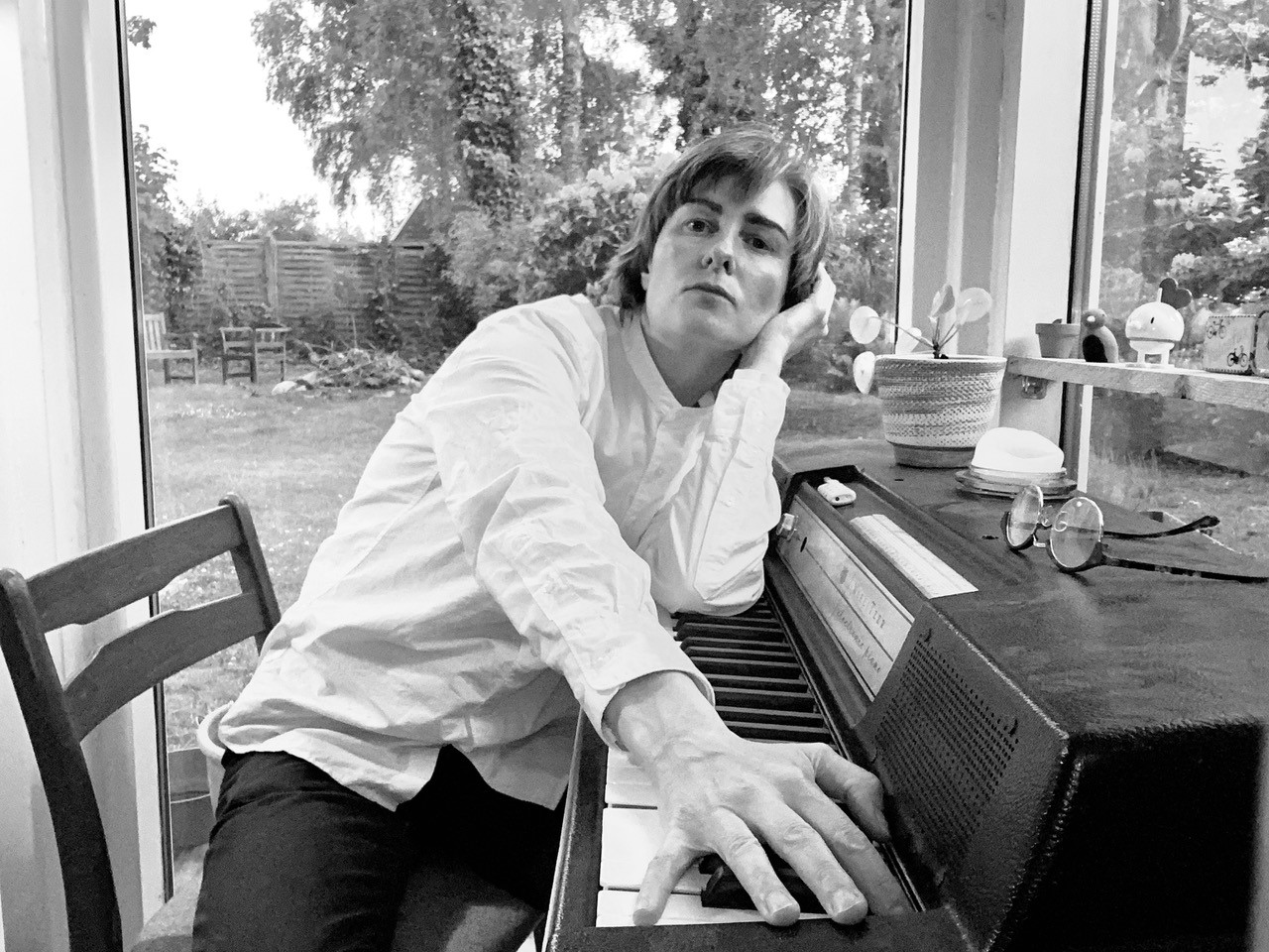 John Lennon spiller et klaver foran et vindue, akkompagneret af Heidi Mortenson.