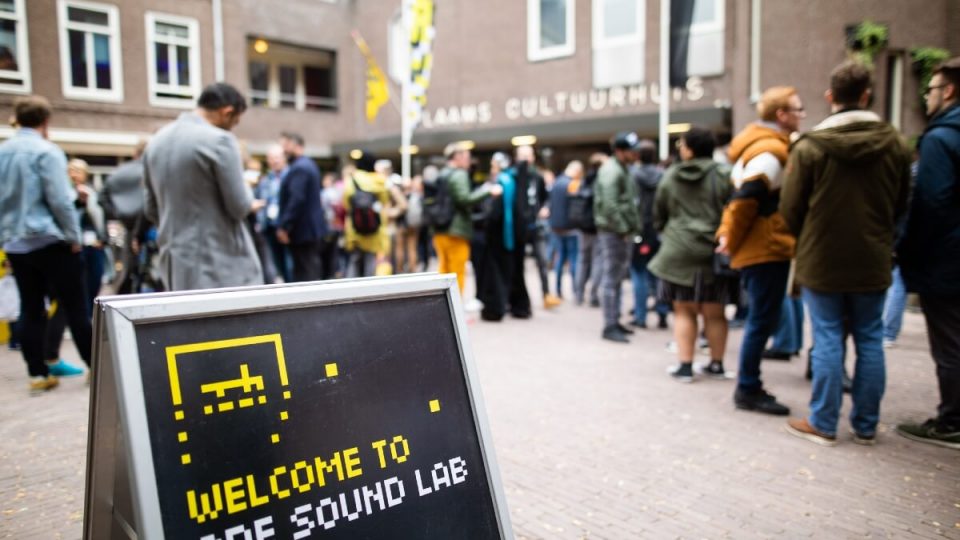En gruppe mennesker står foran et skilt, der siger velkommen til Electronic Fusion Amsterdam.