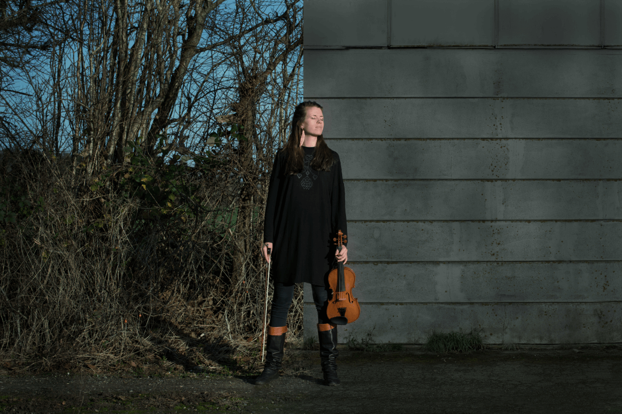 Liv Vester Larsen, en kvinde med en violin, foran en bygning.