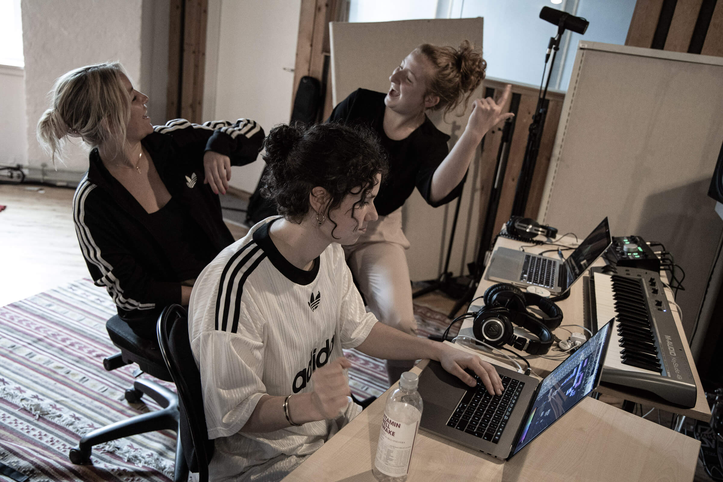 Tre kvinder i et optagestudie med en bærbar computer, der arbejder på deres musikprojekter.