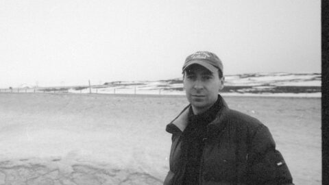 Hjalte Ross står i mørk jakke og kasket, fordybet i den fredfyldte skønhed i et snelandskab under en overskyet himmel.