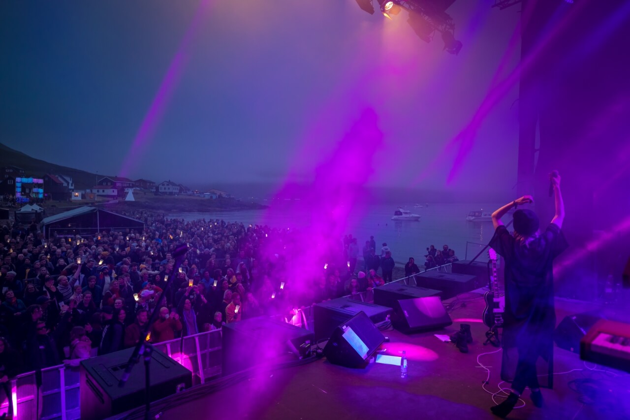 En gruppe mennesker, der står på en scene med lilla lys og skaber en hypnotiserende DJFBA-forestilling.