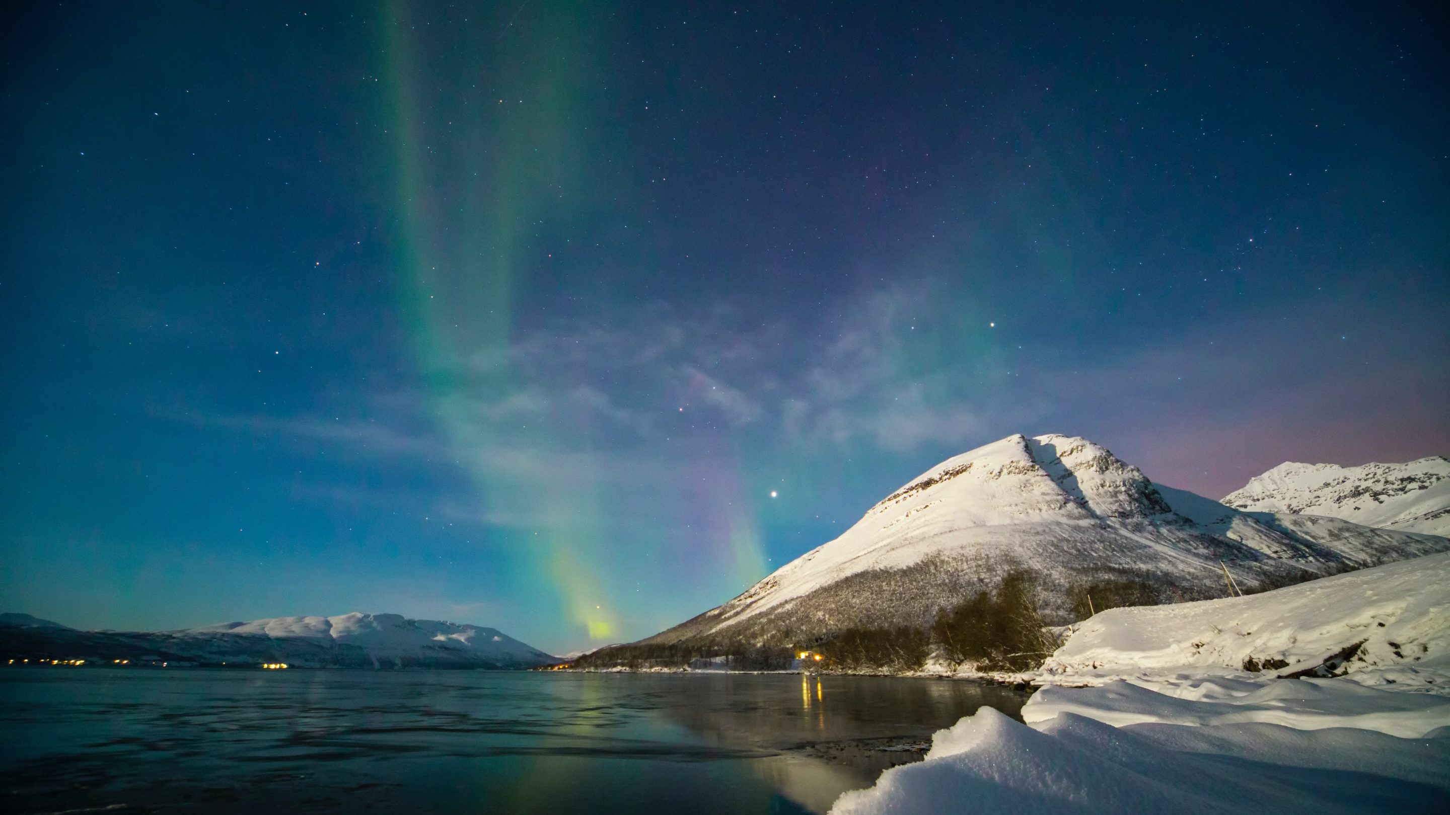 Aurora borealis lyser himlen op over et snedækket bjerg i dette fascinerende Nordisk Kulturfonds projektstøtte-finansierede skue.