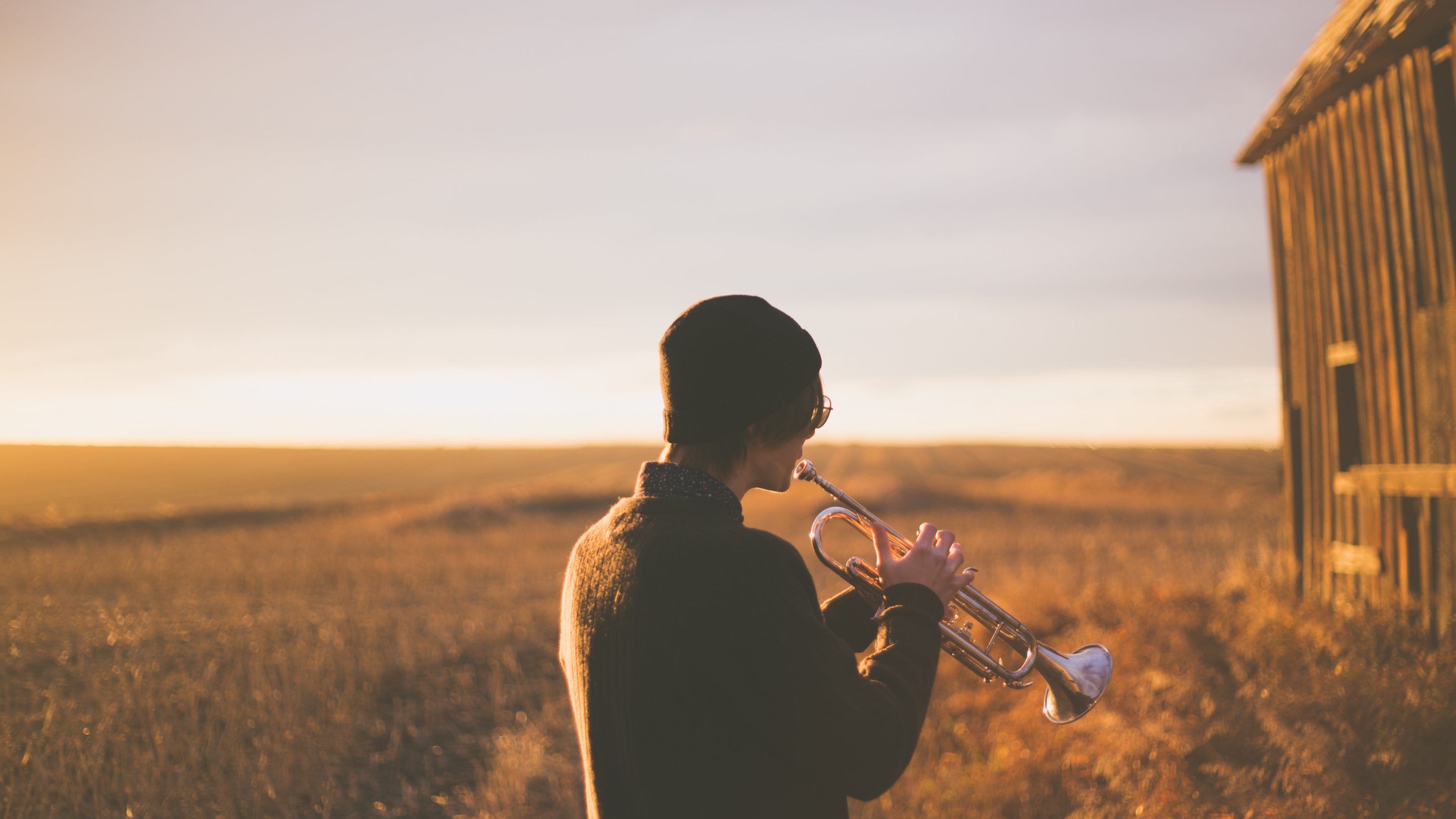 En mand, der spiller en trompet foran en lade, viser sine musikalske talenter.