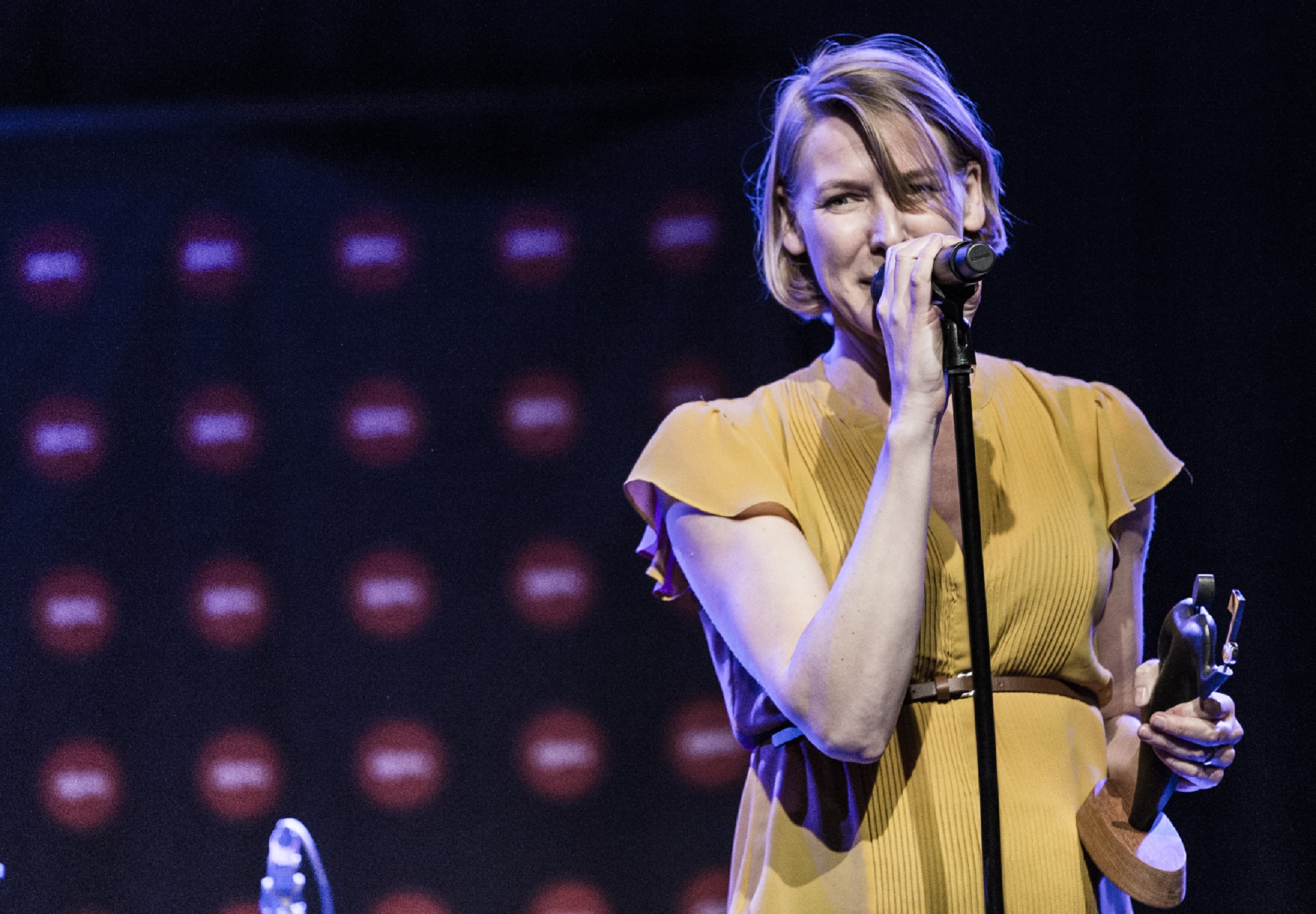 Louise Nipper, iført en gul kjole, synger i en mikrofon under en Mixkursus.