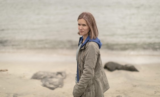 En færøsk kvinde i jakke stående på en strand.