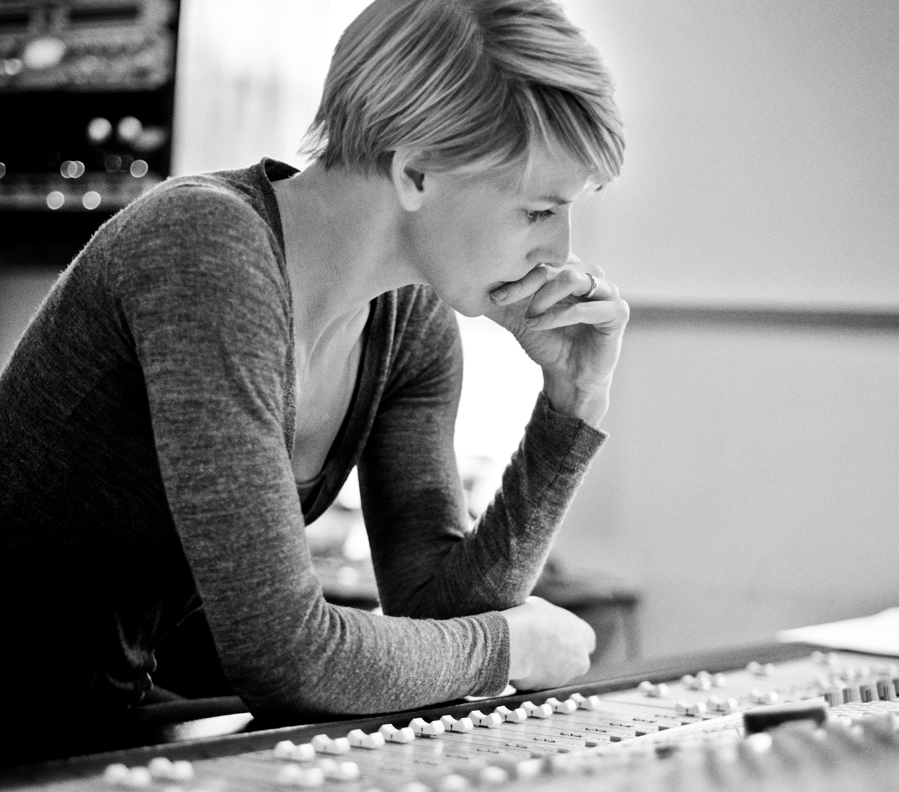Et sort/hvidt foto af en kvinde foran et blandebræt, der skaber soniske harmonier.