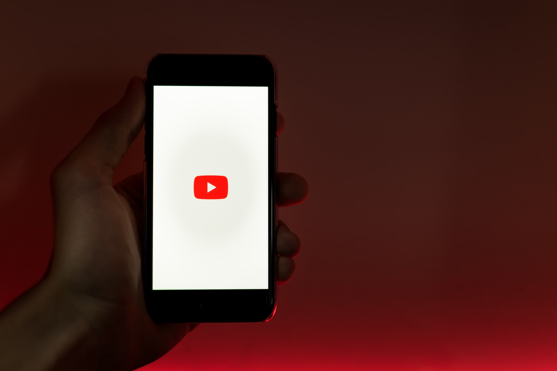 En person, der holder en smartphone, der viser YouTube-logoet.