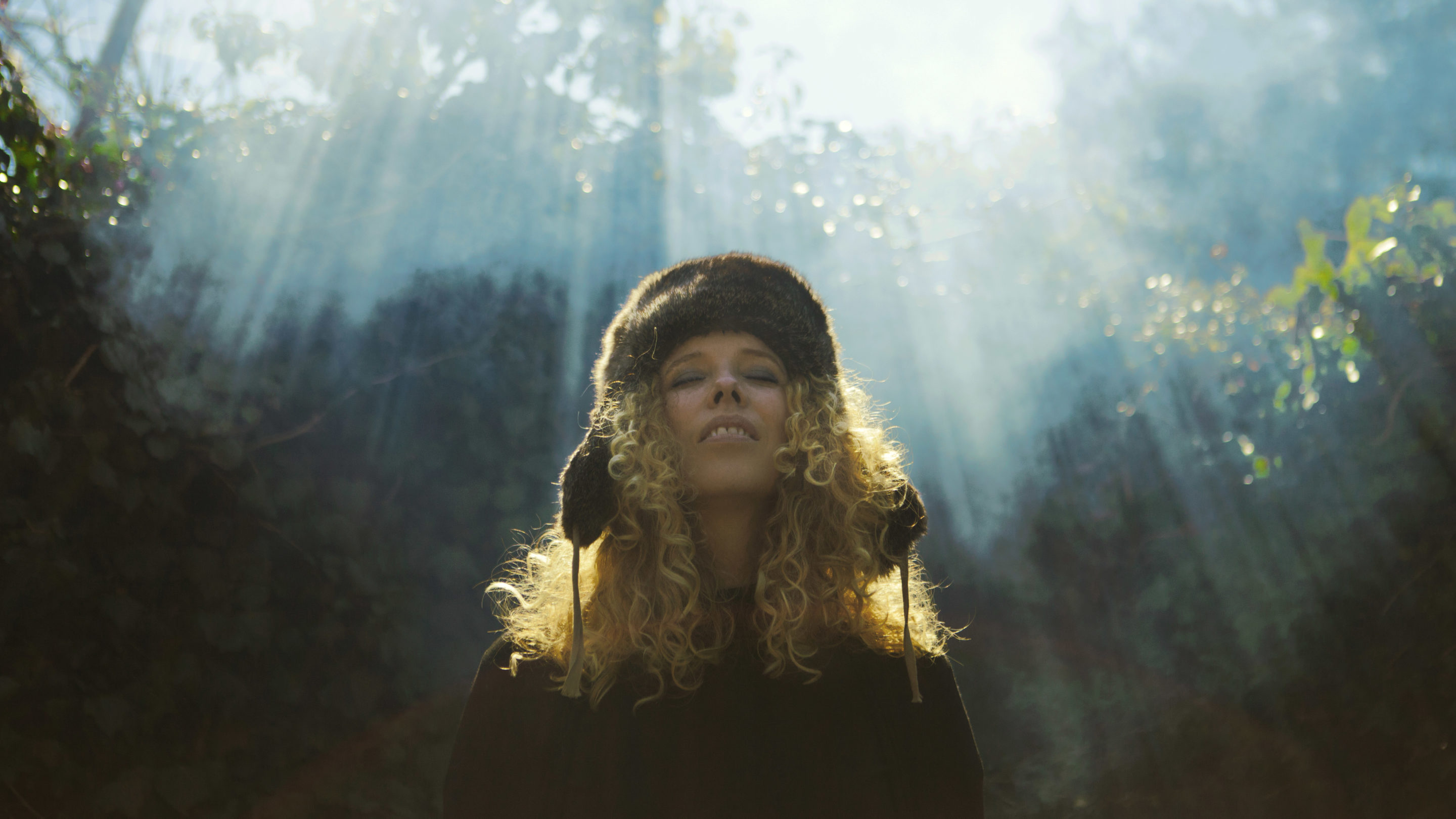 En kvinde i en sort hat, der står i en skov.