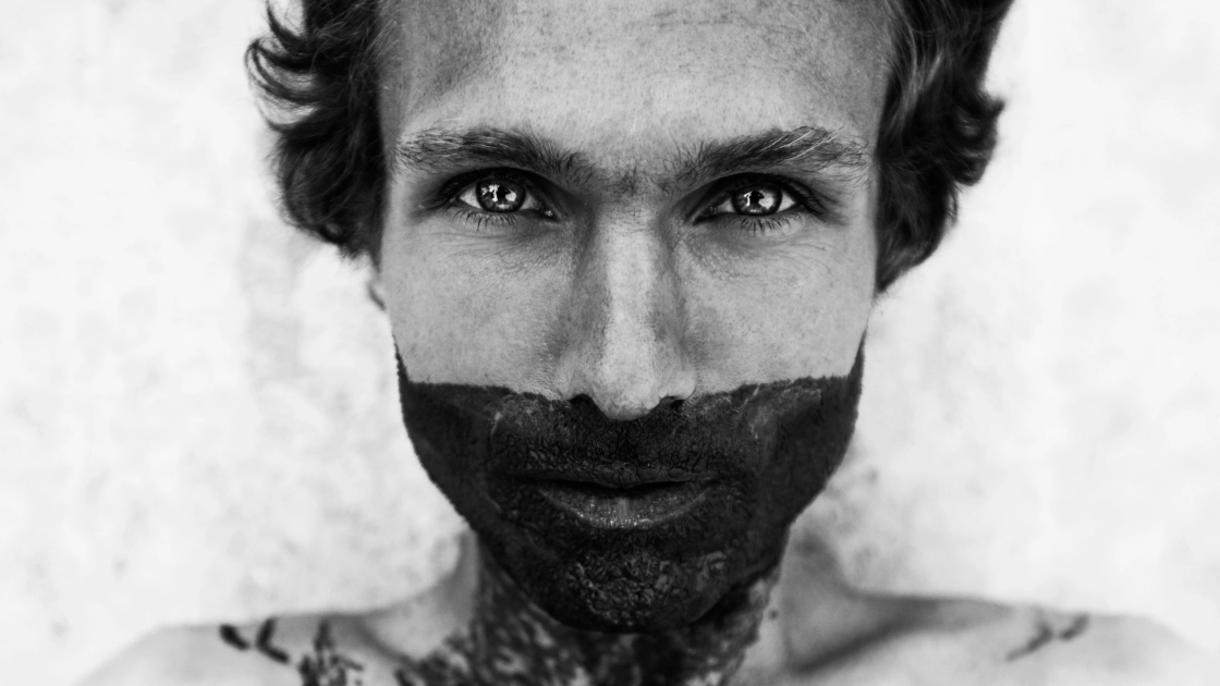 Et kunstnerisk sort/hvid fotografi med en mand med karakteristiske ansigtstatoveringer.