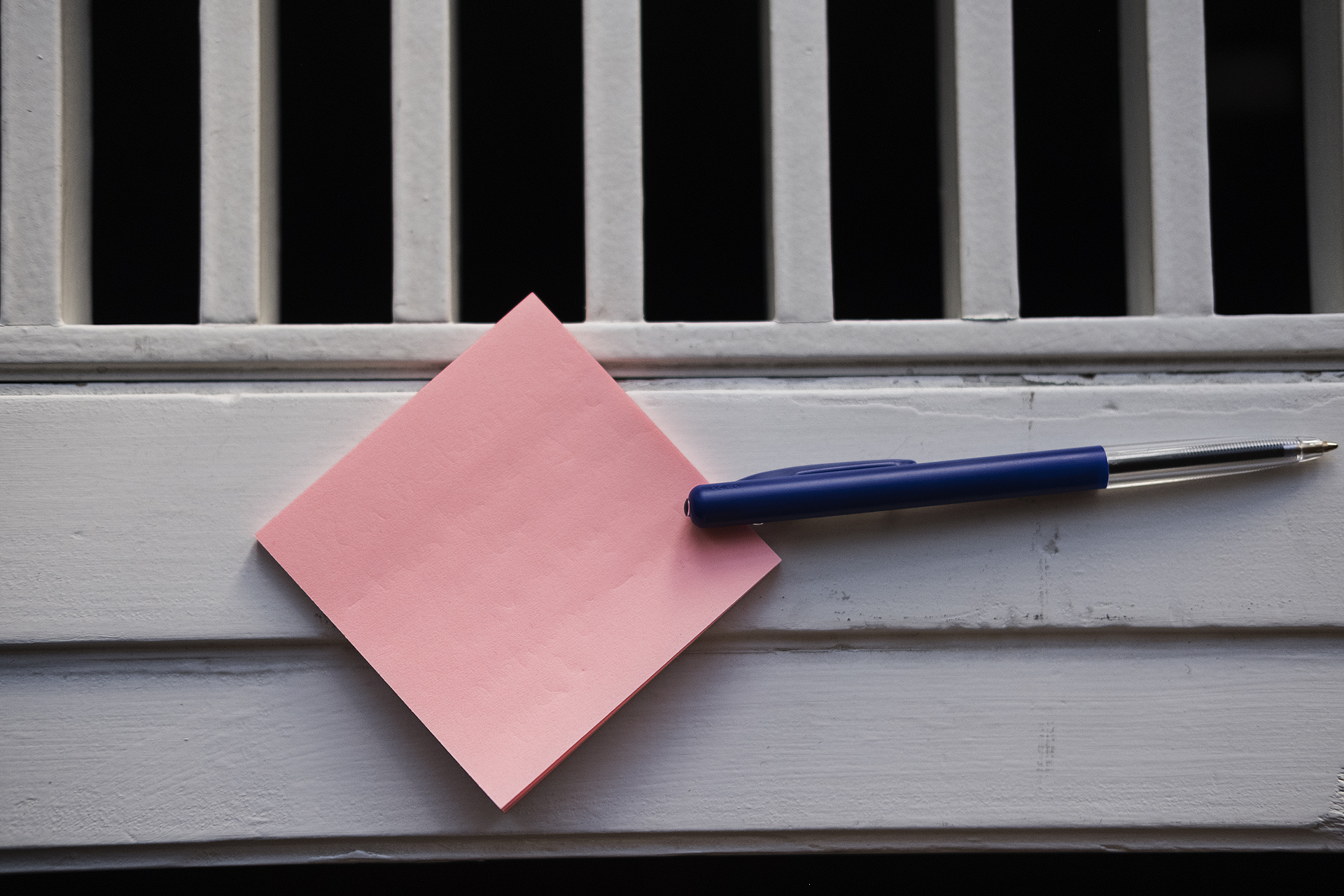 En pink post it-seddel med "28. oktober" skrevet på og en kuglepen placeret ved siden af i en vindueskarm.