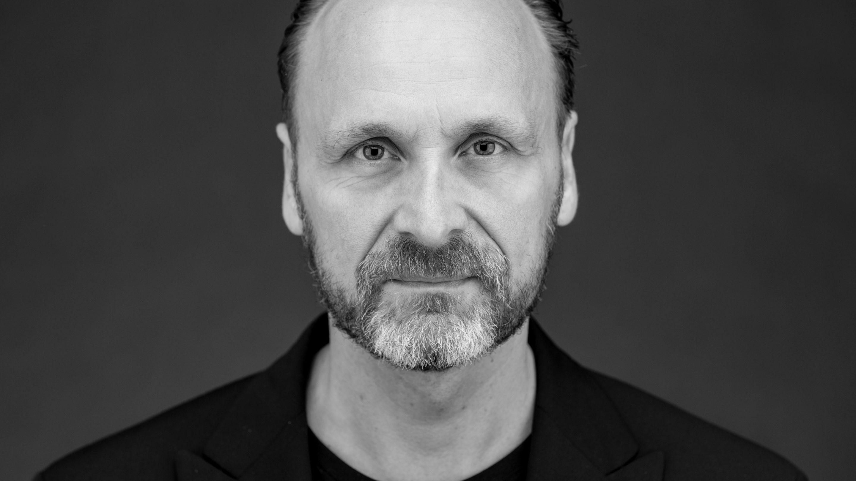 Et sort/hvidt foto af en mand med skæg, taget under en Masterclass af Nippers Netværk med Lars Nissen.
