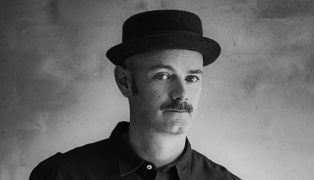 Et sort/hvidt foto af en mand i hat, der fanger essensen af tidløse sangskrivere.