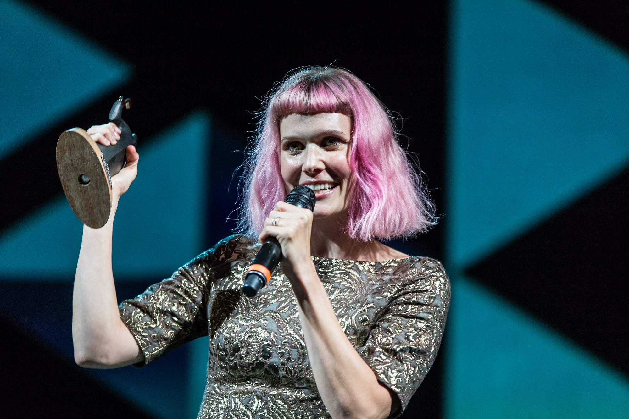 En kvinde med lyserødt hår holder en mikrofon på Autors hæderspriser i 2022.