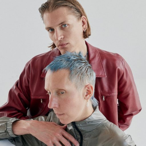 To mænd med livligt blåt hår poserer for et funky billede.