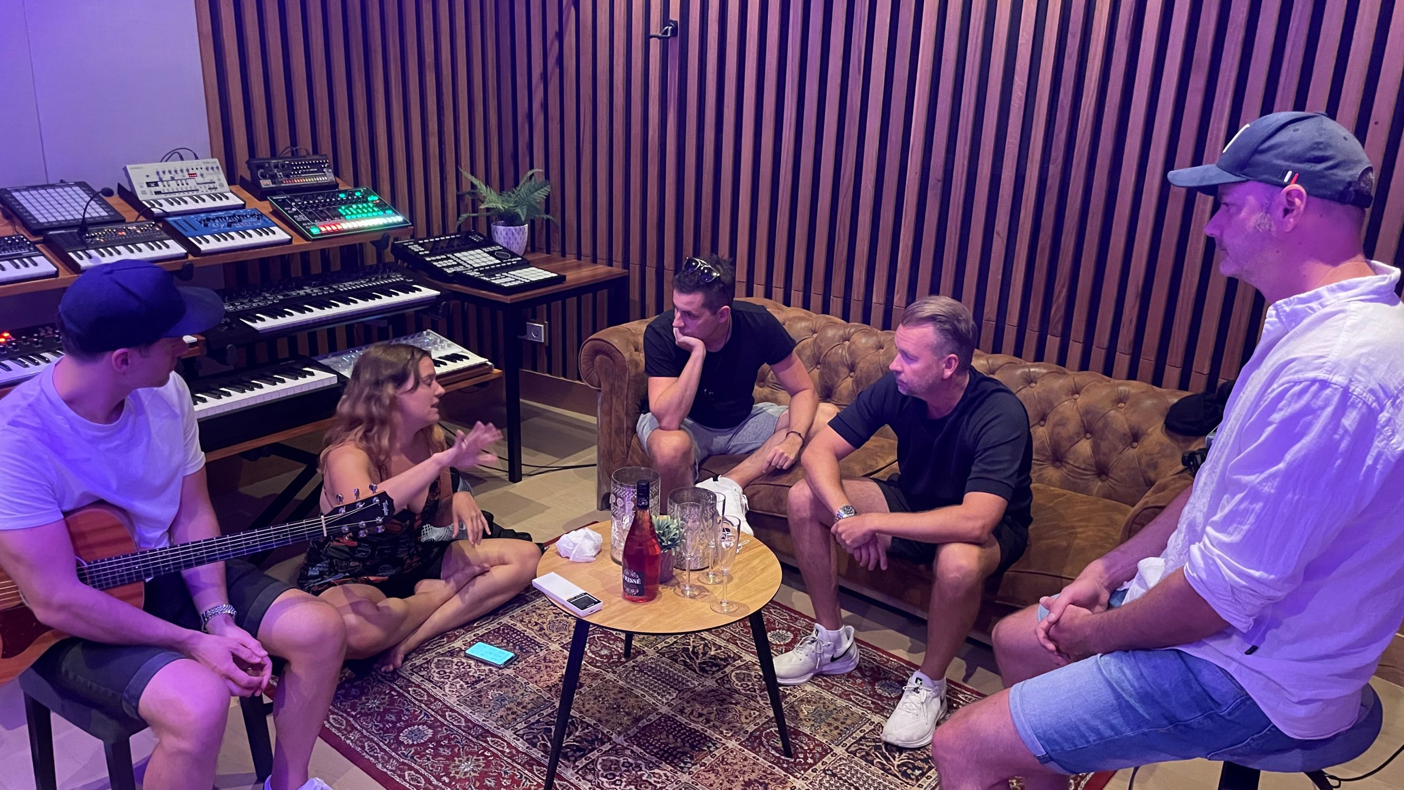 En international gruppe mennesker, der sidder omkring et bord i et optagestudie og forbereder sig til Eurovision Camp 2022.