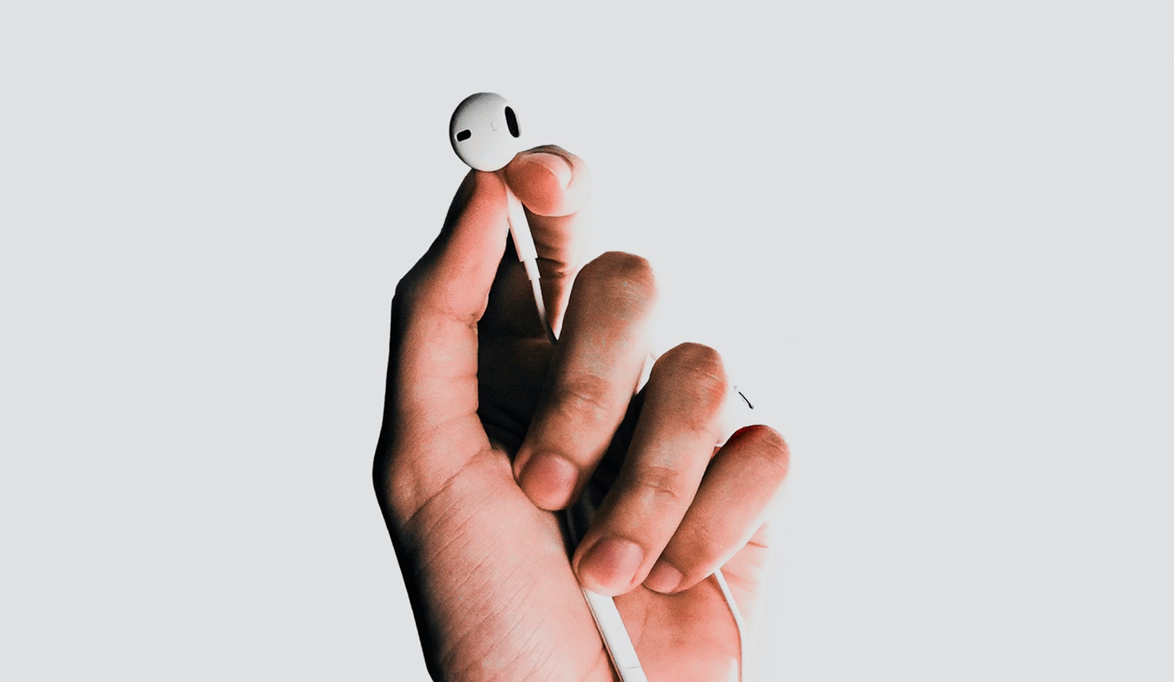 En persons hånd, der holder et æble-airpods, mens han nyder musikstreaming med bedre betalingsmuligheder.