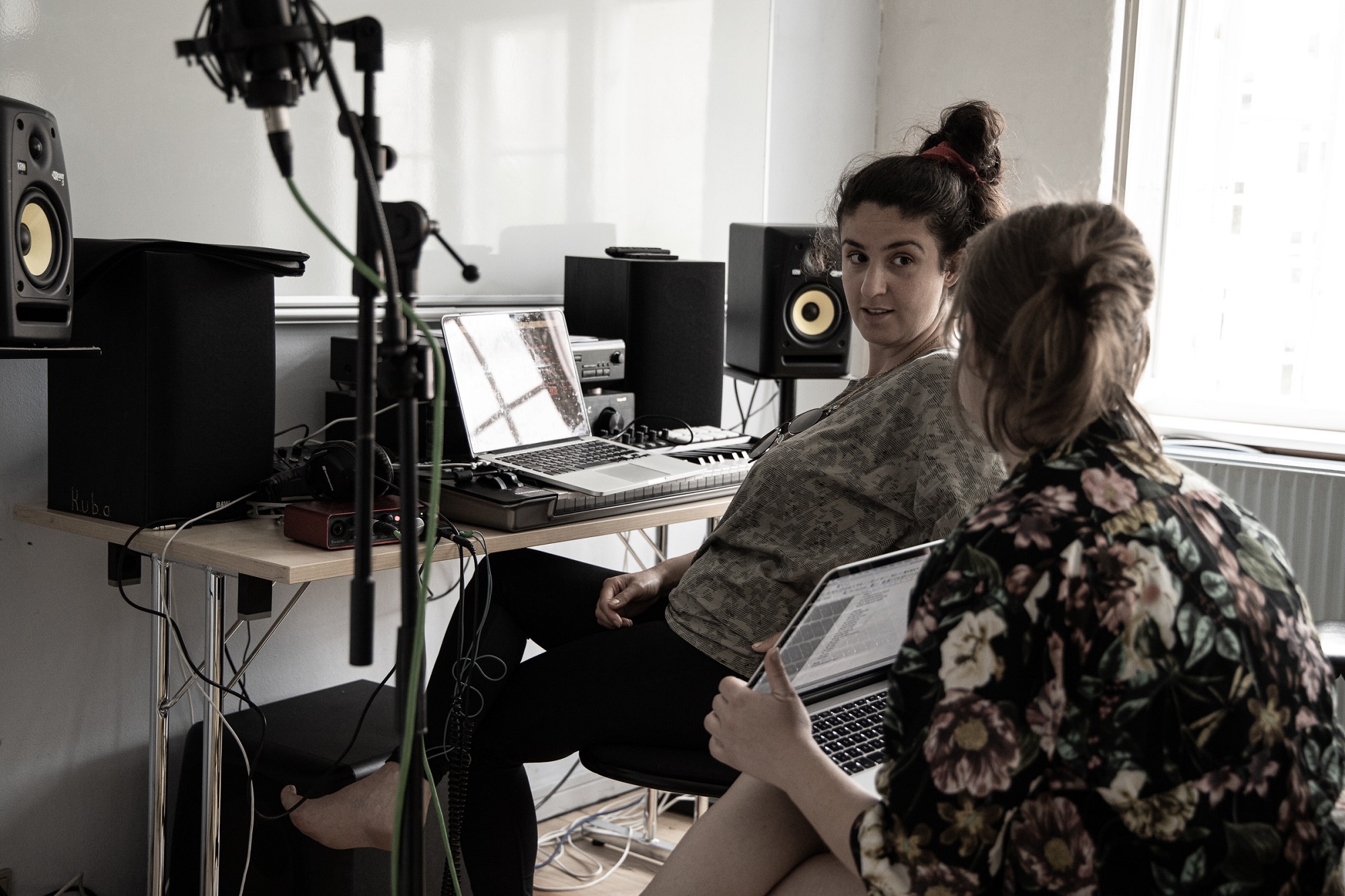 To kvinder deltager i en åben opfordring til musik ved et skrivebord i et optagestudie.