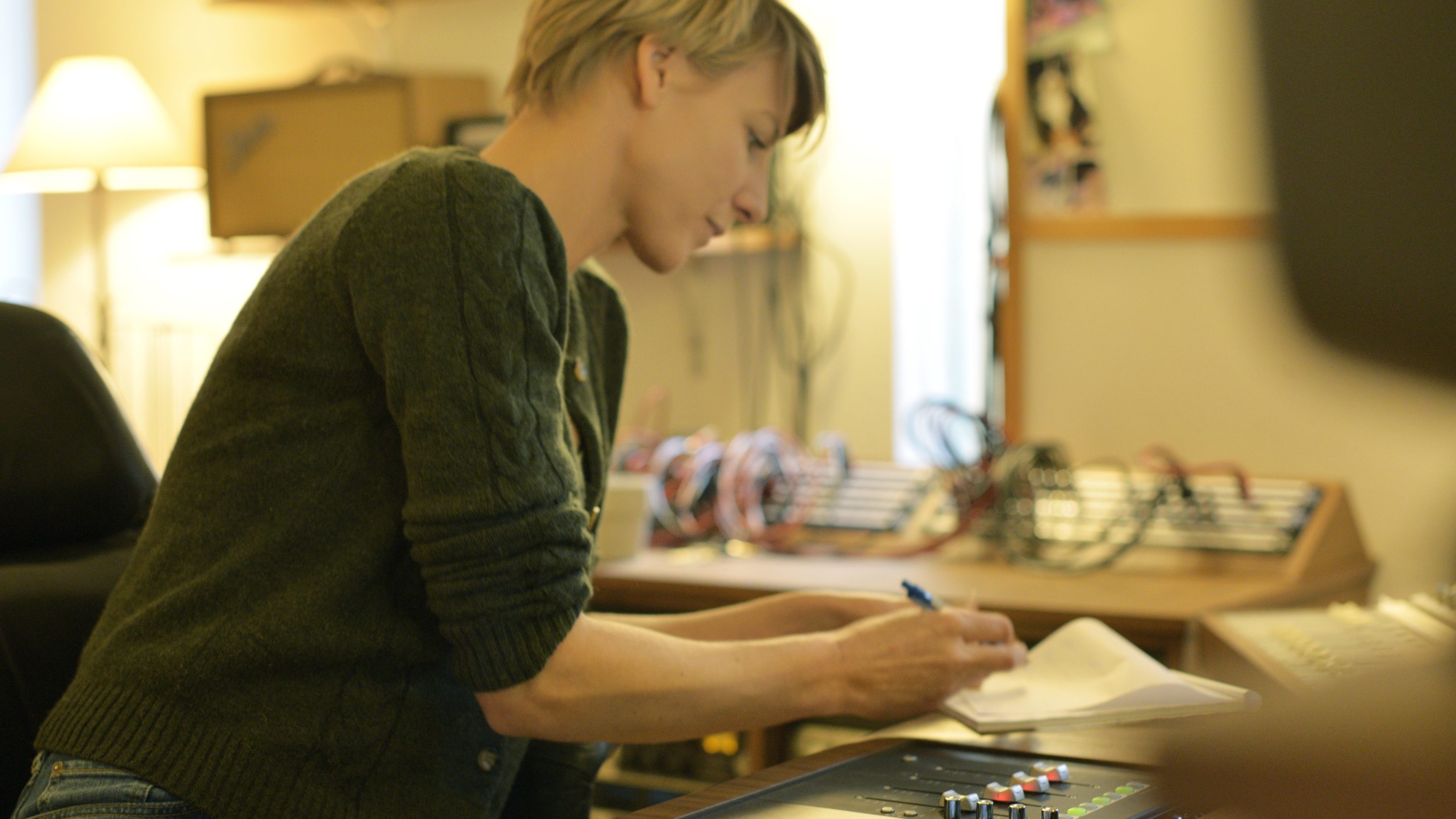 Louise Nipper, en kvinde fra producentnettverket, sidder ved et skrivebord og skriver på et stykke papir.