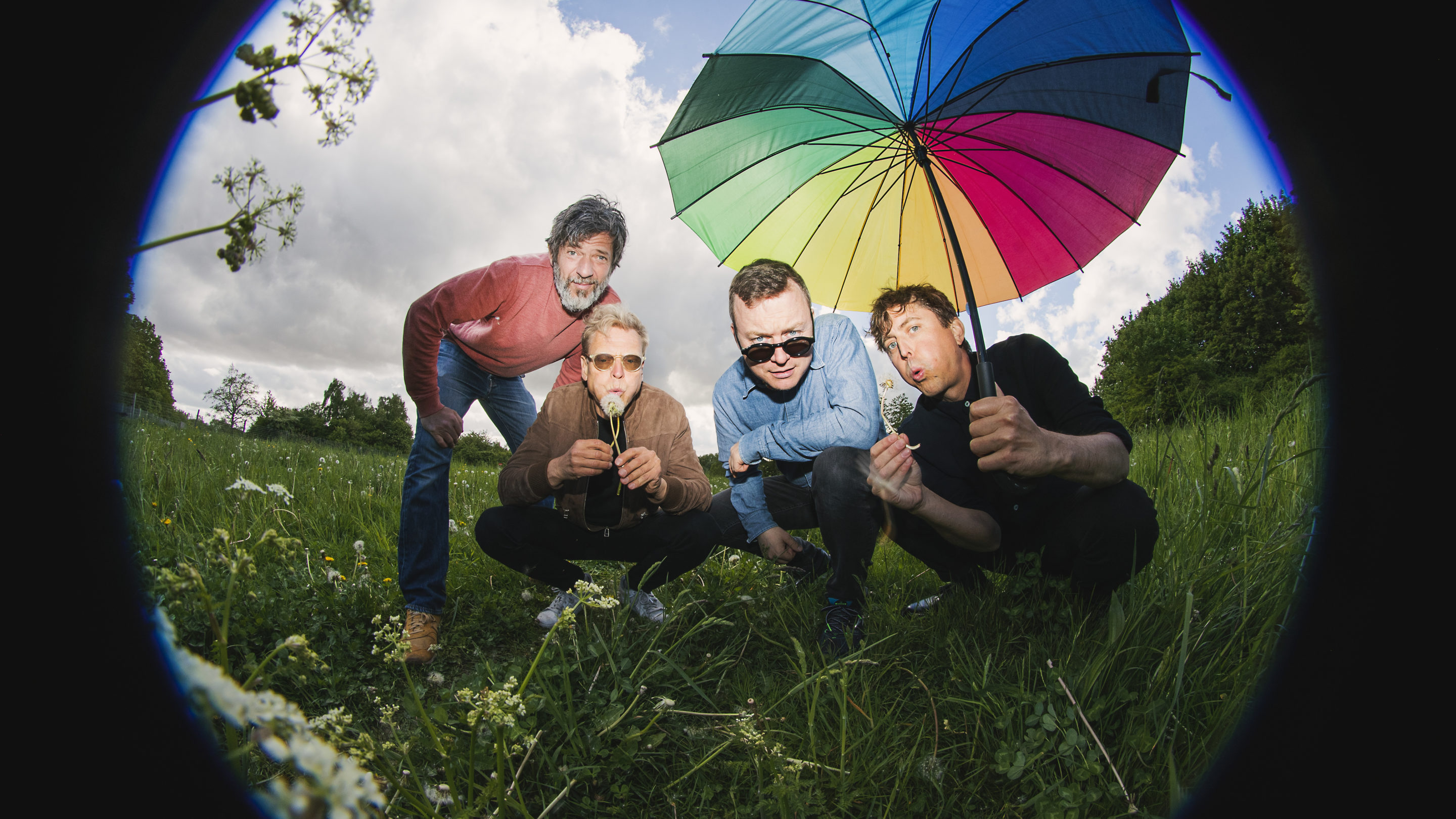 Fire mænd poserer med en paraply på en mark til PR-fotos.