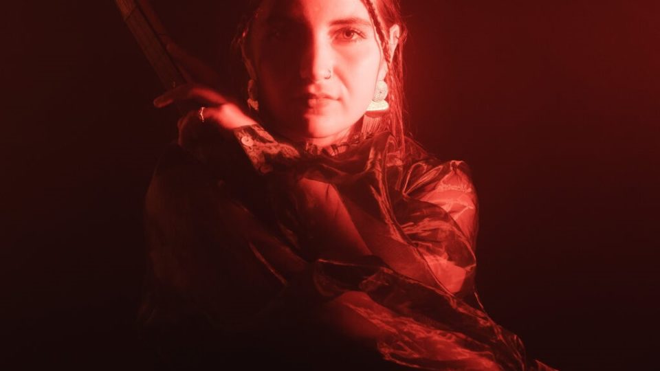 En kvinde med en pistol foran rødt lys ved Hædersprisfesten.