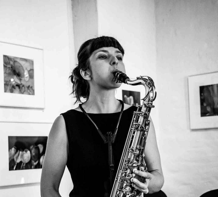 Et sort/hvidt foto af en kvinde, der spiller en saxofon på Osgoods.