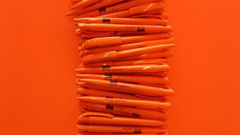 En stak orange blyanter på en orange overflade til en brug.