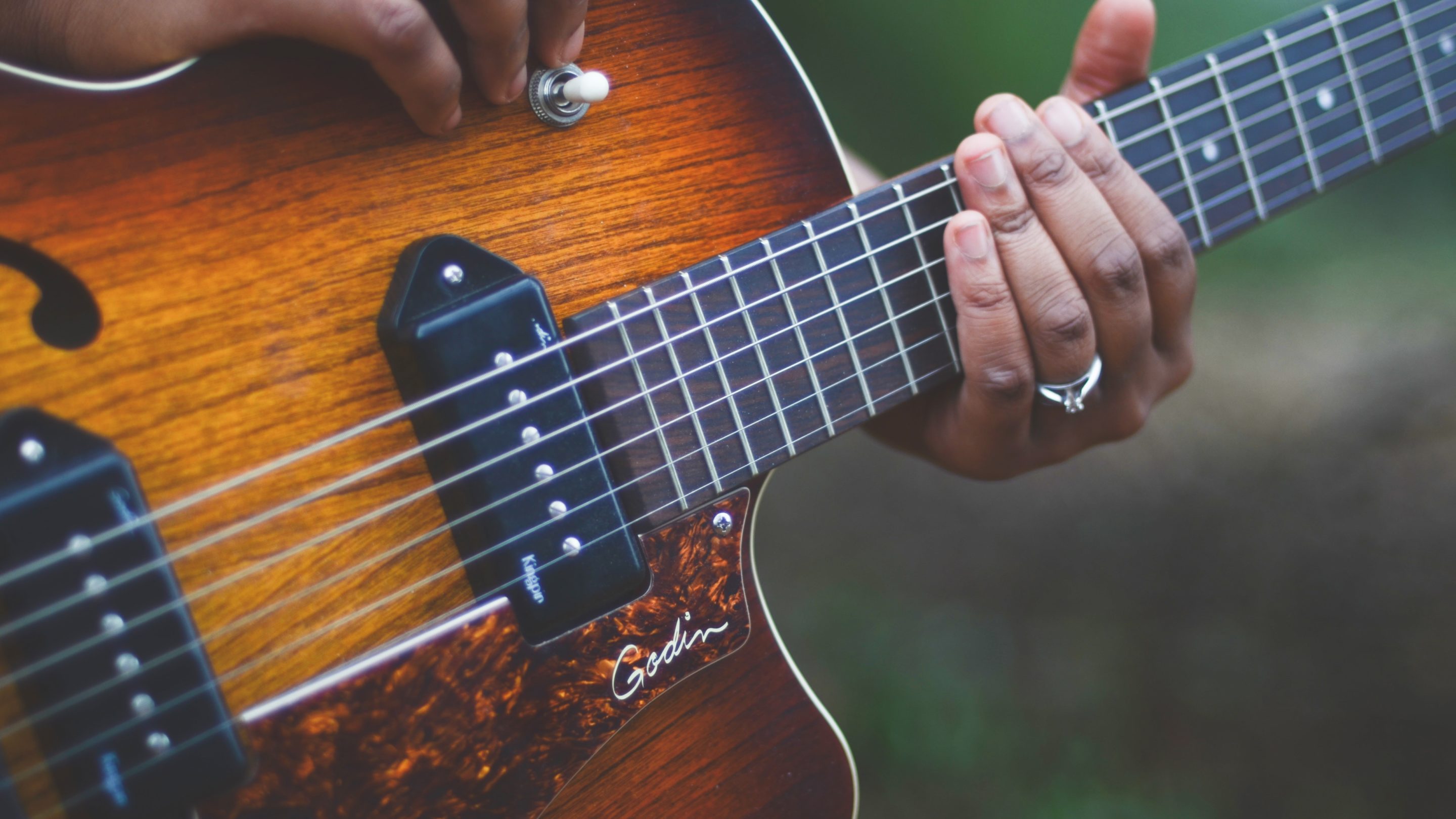 Et nærbillede af en person, der spiller en akustisk guitar, mens han viser indviklede fingerplukningsevner.