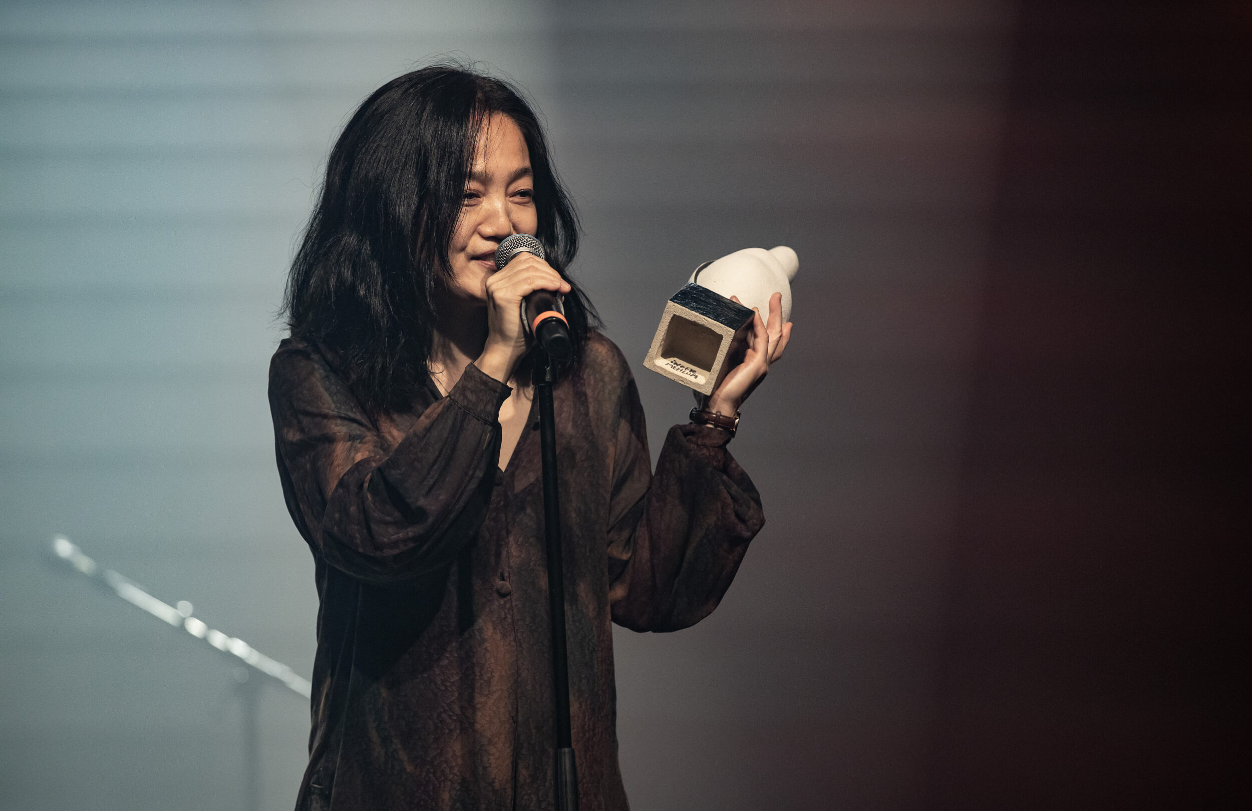 En kvinde, der holder en mikrofon på scenen, mens hun modtager årets hæderspriser for sin enestående præstation.