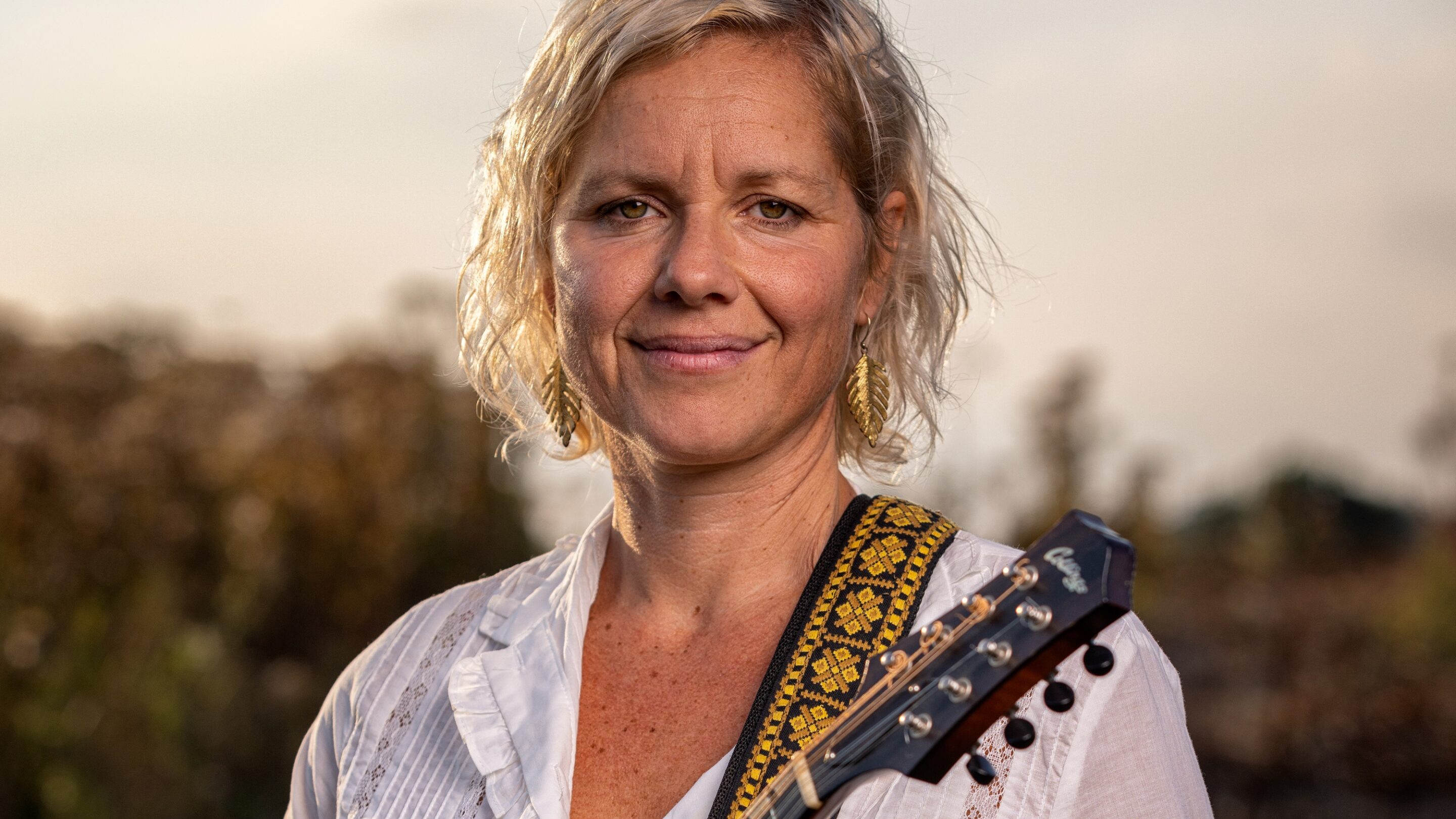En kvinde ved navn Maria Molde med en akustisk guitar på en mark ved Klubben Vest.