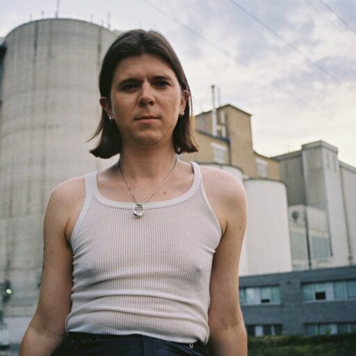 En mand ved navn Petra Skibsted i en tanktop stående foran en silo.