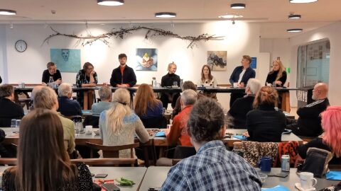 En gruppe bestyrelsesgenvalgt sidder ved borde i et rum.