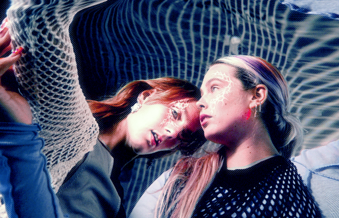To kvinder, Ditte Angelo og eQ Saturdays, står i et lokale med et net over hovedet under en musikproduktion.