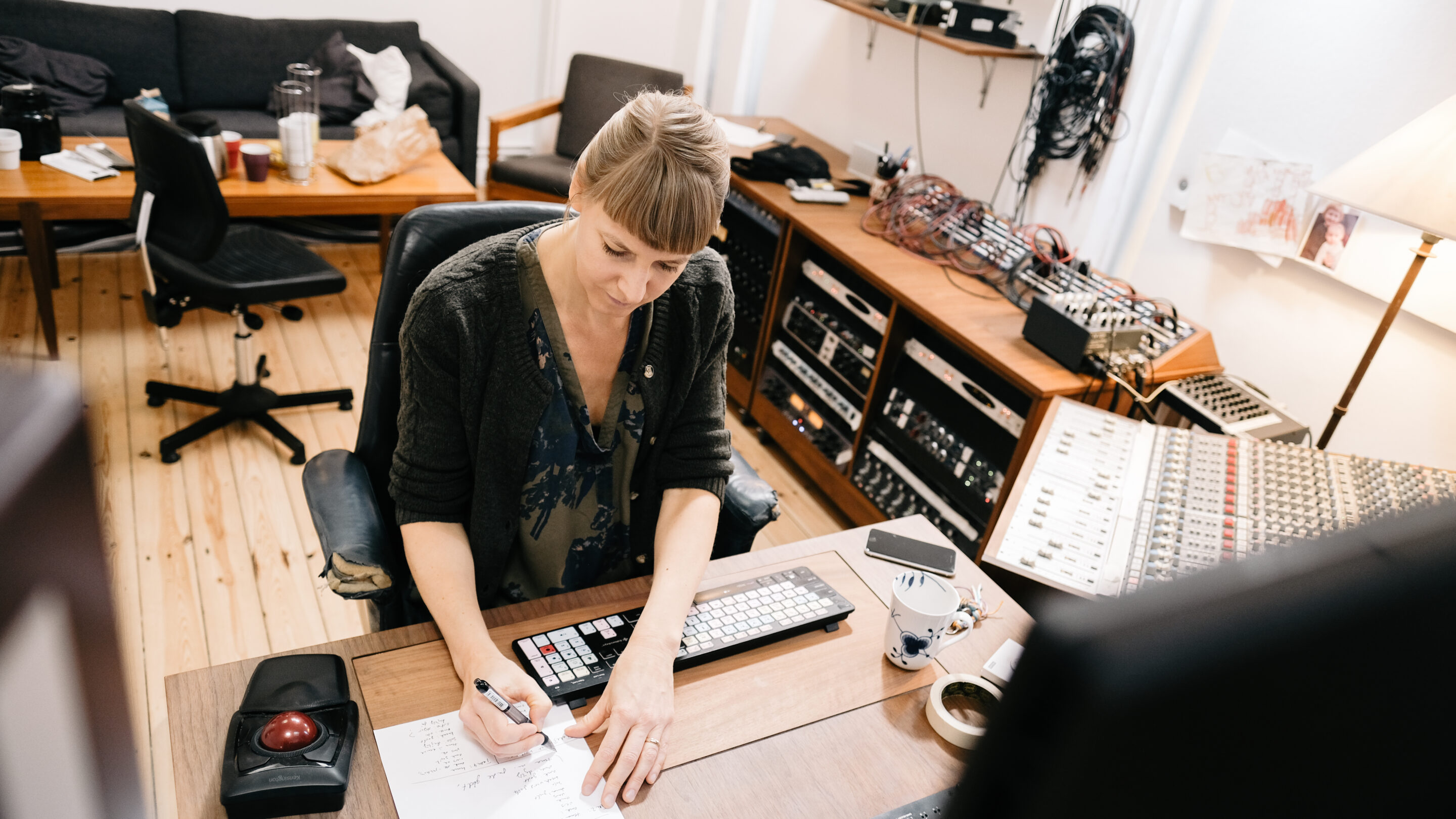Louise Nipper, en kvinde, sidder ved et skrivebord i et optagestudie under et mixkursus (produktionskursus).