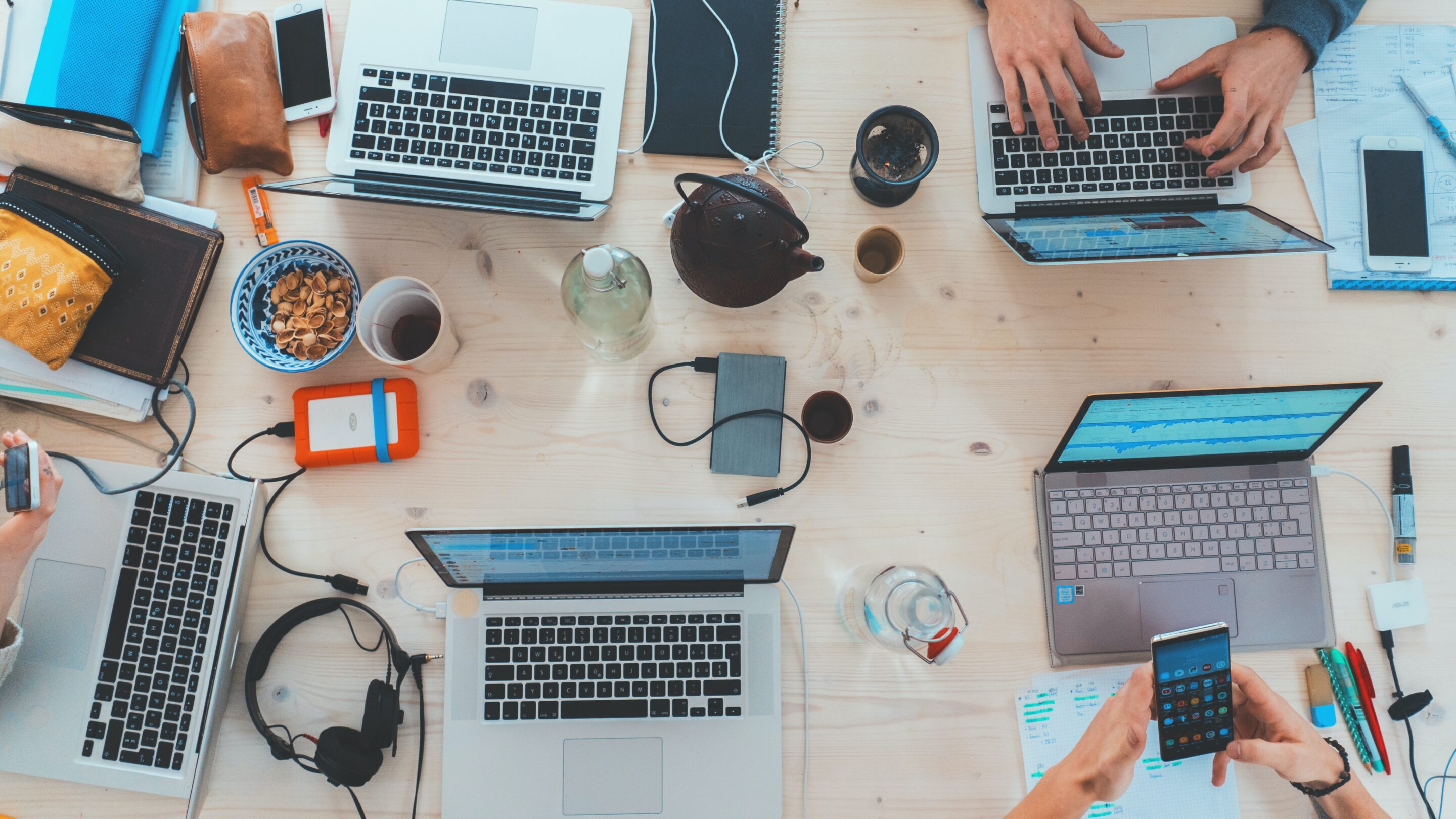 Kontorkollektivet - En gruppe mennesker, der sidder rundt om et bord med bærbare computere, samarbejder og arbejder.