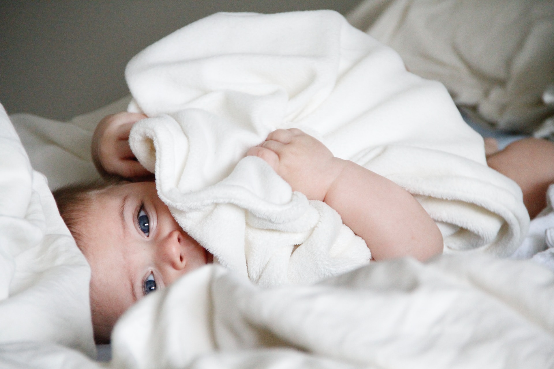 En nyfødt baby gemmer sig under et hyggeligt tæppe i en seng, mens dets nybagte musikforældre (nybagte musikforældre) deltager i spændende workshops.
