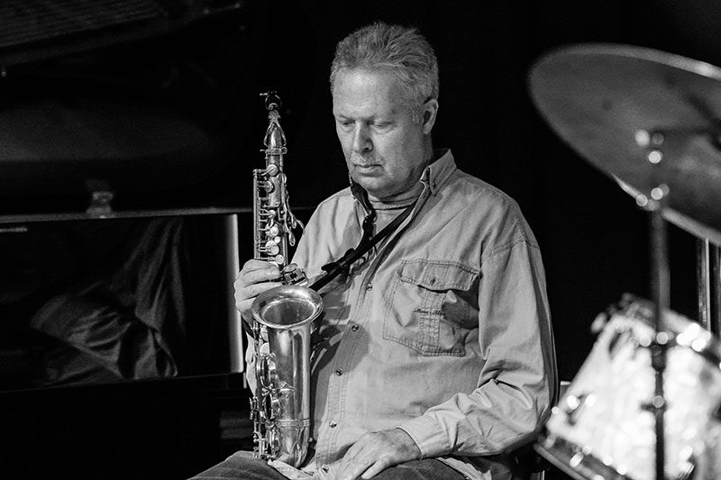 Et sort/hvidt foto af en mand, der spiller saxofon i Osgoods Netværk.