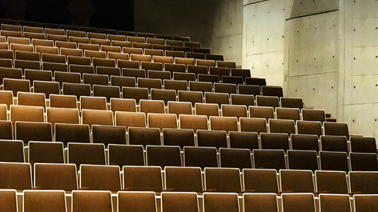 Et tomt auditorium med sæderækker venter på musikeren, der skaber en atmosfære fyldt med musik og glæde.