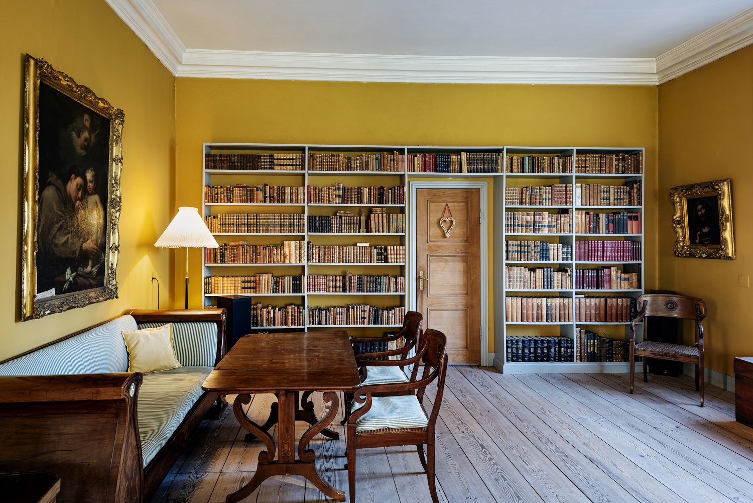 Et levende rum med gule vægge prydet af bogreoler.