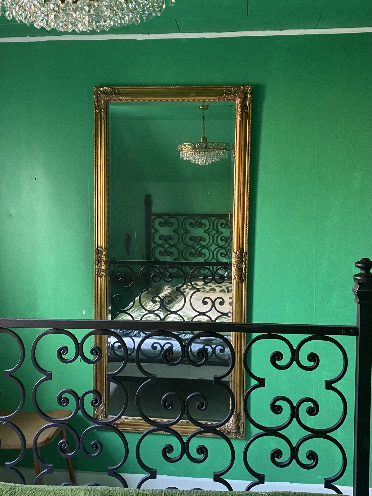 Et grønt soveværelse med et spejl, en lysekrone og Kaninhullet.