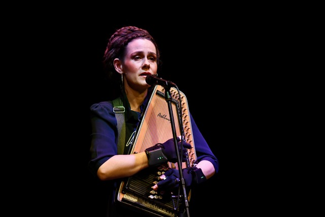 En kvinde, Jullie Hjetland, spiller en akustisk guitar foran en mikrofon i Klubben Vest.
