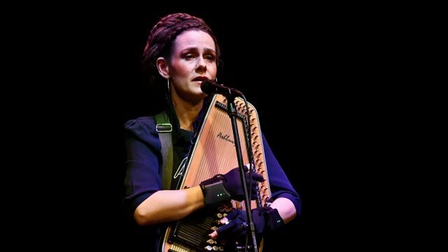 En kvinde, Jullie Hjetland, spiller en akustisk guitar foran en mikrofon i Klubben Vest.